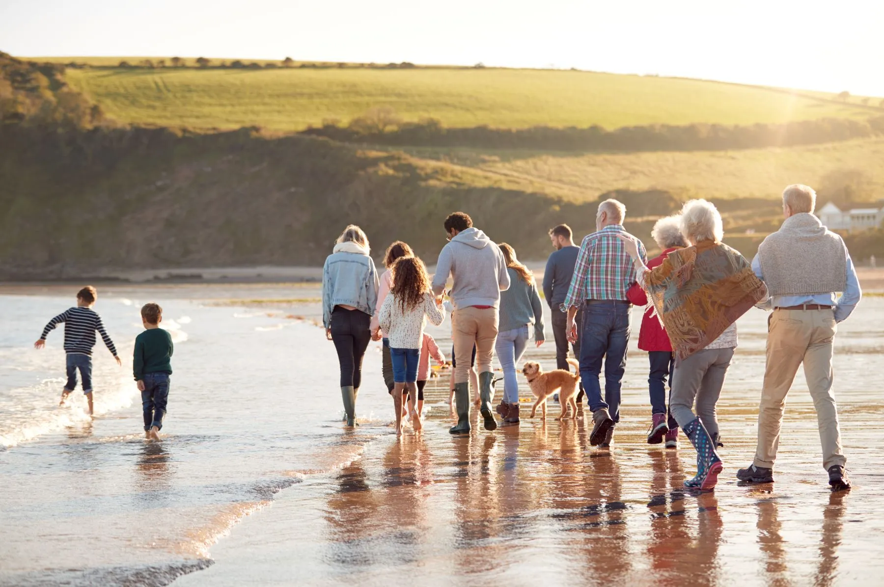A family strolls along the beach at sunset